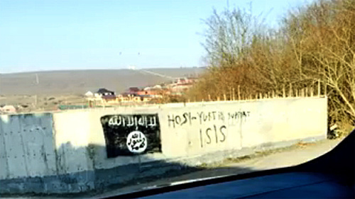 An image of the flag used by the militants of the "Islamic State" (recognized on December 29, 2014, by the Supreme Court of the Russian Federation as a terrorist organization) on a wall of the building in the village of Khosi-Yurt. Photo: screenshot of a video ISIS in Khosi-Yurt / IG in Chechnya, http://www.youtube.com/watch?v=n2sVCqLfPp0