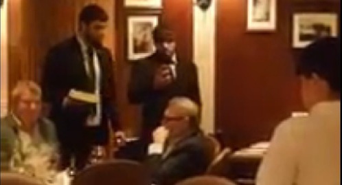 Two men who attacked Mikhail Kasyanov standing with a cake near the politician at a Moscow restaurant. Screenshot of a video of the attack on the site tv.mk.ru