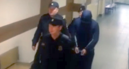 Policemen accompany Magomed Guchigov to the court hearings. Screenshot of video coverage by NTV channel, Ntv.ru/video