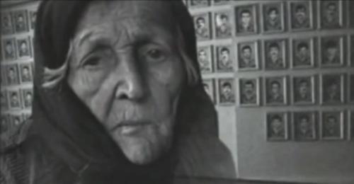 An elderly woman near the photos of the victims of war and deportation. Photo: screenshot of the video on the YouTube channel vainakh38
