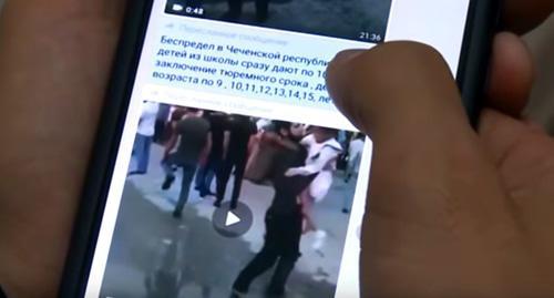 Playing video on a smartphone where convicts' relatives express their indignation at the verdicts. Screenshot from video broadcasted by "Grozny" TV Channel: https://www.youtube.com/watch?v=ljPg7TqLENs