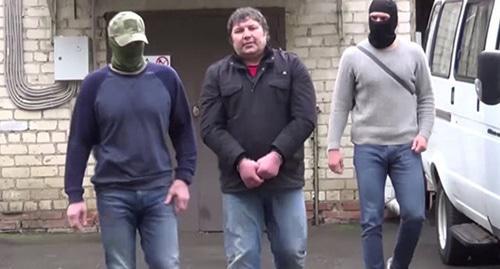 Khazvakha Cherkhigov (centre) is detained by law enforcers. Screenshot from FSB video 