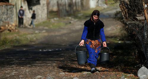 A woman carrying buckets of water in a street of a village Tsinubani in Pankisi Gorge, Georgia. Photo: REUTERS: David MdzinarishviliHEADLINE:A