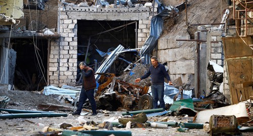 Men walking among the ruins after shelling in Stepanakert on October 13, 2020. Photo: REUTERS / Stringer