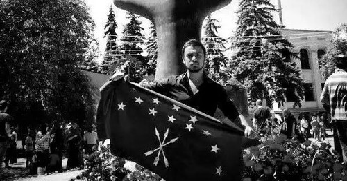 Nartan Kylych holding the Circassian flag in front of a monument to victims of the Caucasian War in Nalchik. Photo: Aslan Schakue, Fatima Tlisova and Olga Efendieva-Begret, https://www.facebook.com/photo.php?fbid=10153411014089002&set=a.10150641558564002.436428.531449001&type=1&fref=nf&pnref=story