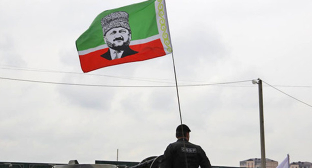 An officer of the Chechen Special Rapid Response Unit (SOBR) with a flag of the Republic with a portrait of Akhmat Kadyrov. May 9, 2015. Grozny. Photo by Magomed Magomedov for the "Caucasian Knot"
