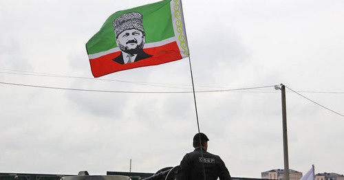 An officer of the Chechen Special Rapid Response Unit (SOBR) with a flag of the Republic with a portrait of Akhmat Kadyrov. May 9, 2015. Grozny. Photo by Magomed Magomedov for the "Caucasian Knot"