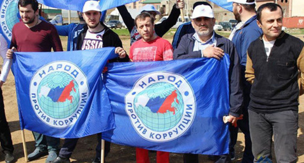 Activists of the "People Against Corruption" Party holding flag. Photo: http://www.dagestanpost.ru/novosti/vrepublice/30593-aktivisty-iniciativnoj-gruppy-narod-protiv-korrupcii-vyshli-na-stroitelstvo-narodnogo-stadiona-v-maxachkale
