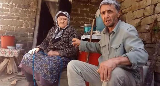 Ramazan Djalaldinov with an elderly woman in the village of Kenkhi. Screenshot of a video appeal