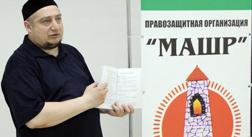 Magomed Mutsolgov near the poster with the "Mashr" logo. Photo http://mchenrycitizenstaxwatch.org/blogs/342/posts/28890