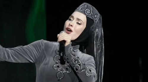 Aina Getagazova signing at the concert in Grozny. Screenshot from Youtube video posted by Chechnya.095: https://www.youtube.com/watch?v=nzOASGDmYYE Aina Getagazova signing at the concert in Grozny. Screenshot from Youtube video posted by Chechnya.095: https://www.youtube.com/watch?v=nzOASGDmYYE