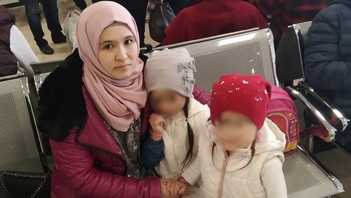 Elmira Kenzhibulatova with her children in an airport. Photo courtesy of Rasul Kenzhibulatov