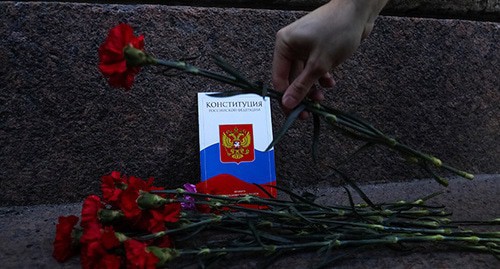 A hand with flowers near the Constitution booklet. Photo: REUTERS/Anton Vaganov