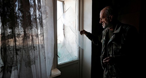 A man removes glass fragments from a window damaged as a result of shelling of Stepanakert, October 13, 2020. Photo: REUTERS/Stringer