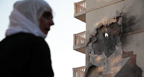 A woman at a destroyed building in Syria. Photo: REUTERS/Sertac Kayar