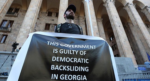 Activist holding a poster at a rally demanding the resignation of the Prime Minister and the government of Georgia, Tbilisi, July 17, 2021. Photo: REUTERS/Irakli Gedenidze