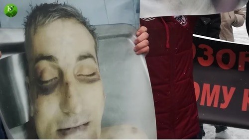 A poster showing traces of torture on Vladimir Tskaev's face. Screenshot of the video by the "Caucasian Knot" https://www.youtube.com/watch?v=1Fwh_EBWCo0