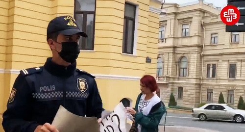 Policemen took the poster away from Gyulnara Mekhtieva, a feminist activist. Screenshot of the video https://www.facebook.com/watch/?v=670963433871546&amp;ref=sharing 