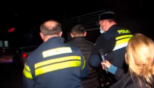 Police take away the attacker on journalists. Image made from video posted by Formula channel at: https://formulanews.ge/News/66843
