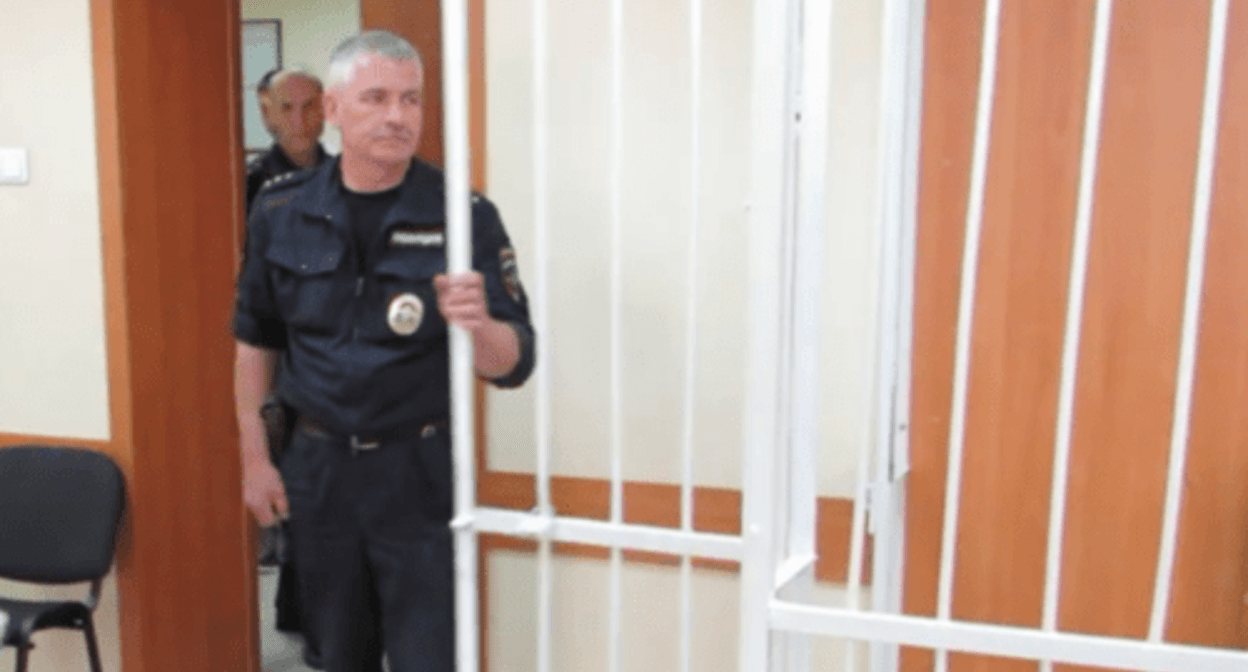 A law enforcer at the cage in courtroom. Screenshot of a video "Berdsk Online" https://www.youtube.com/watch?v=-W8kL4as5N0