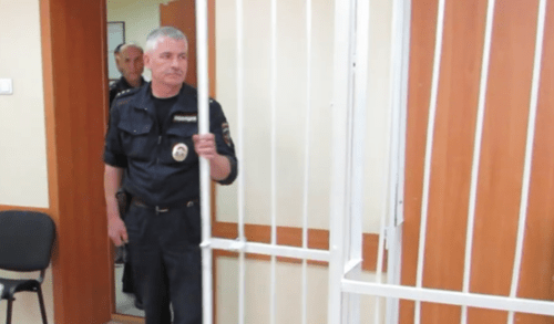 A law enforcer at the cage in courtroom. Screenshot of a video "Berdsk Online" https://www.youtube.com/watch?v=-W8kL4as5N0