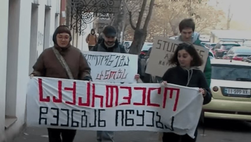 Students of the Academy of Arts with a poster saying, "Georgia begins with us." Screenshot of a video posted by the “Pirveli” TV Company on January 8, 2025 https://tvpirveli.ge/ka/siaxleebi/sazogadoeba/91147-saqartvelo-itskeba-chvengan-universitetebshi-protestma-ipetqa