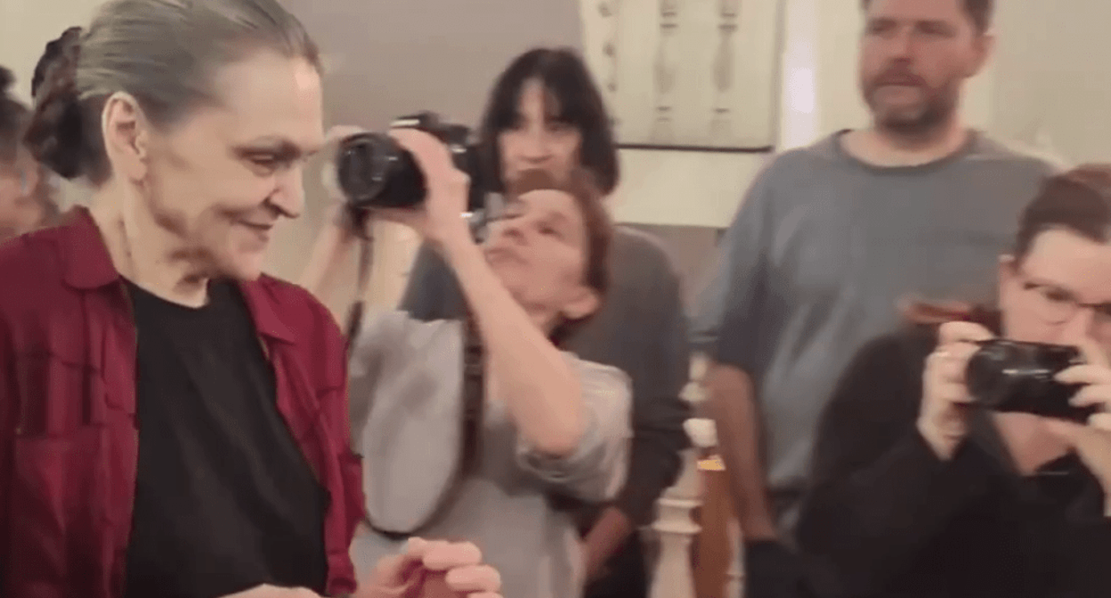Nadezhda Kevorkova in handcuffs is lead to a courtroom. Screenshot of a video posted by the RusNews on March 12, 2025, https://t.me/rusnews/68047