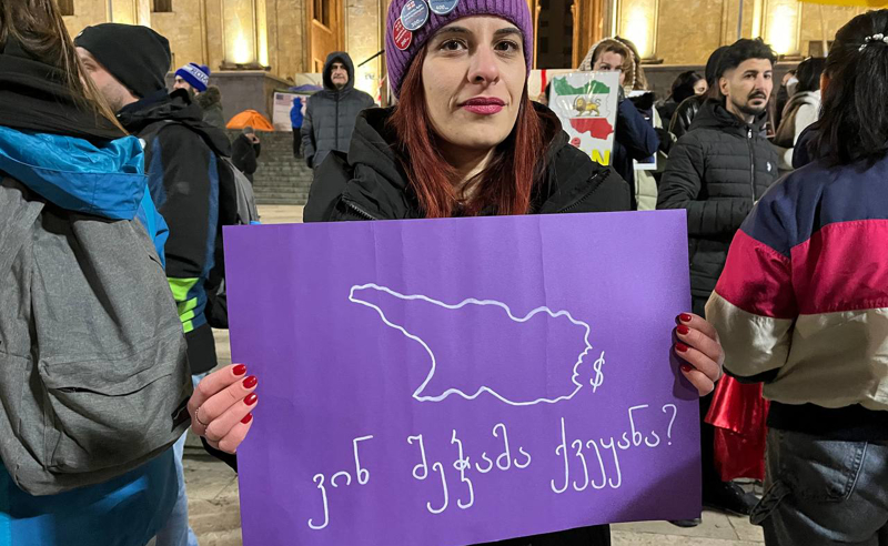 A protester in Tbilisi on the 427th day holds a banner reading, "Who ate the country!" Photo: TV Pirveli / https://tvpirveli.ge/ka/siaxleebi/sazogadoeba/120155-utskveti-protestis-427-e-dge-rustavelis-gamzirze-saprotesto-aqtsia-mimdinar