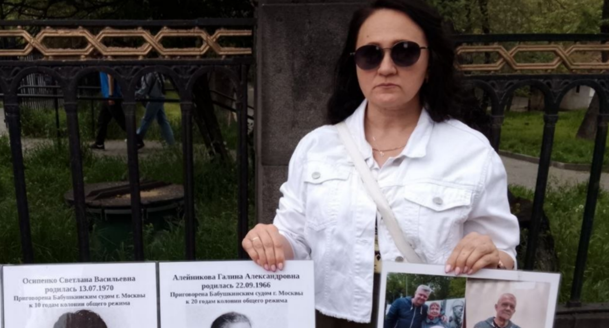 A picketer holds signs. Screenshot from RusNews photo from May 2, 2026, https://t.me/rusnews/84132.